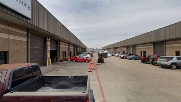 Drive aisle between buildings, roll-up doors open along the bay line