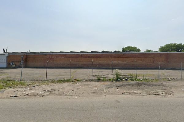 Street-level view of the fenced studio campus wall with sawtooth roofline