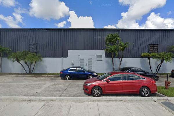 Street-level view of the gray metal industrial building frontage with palms