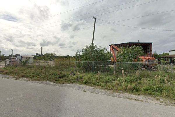 Street-level view of fenced industrial yards along 49th Terrace N