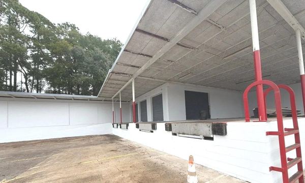 Covered dock bay with roll-up doors and dock levelers, freshly repainted